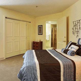 A well-decorated bedroom featuring a bed with striped bedding and decorative pillows, a closet with sliding doors, and wall art.