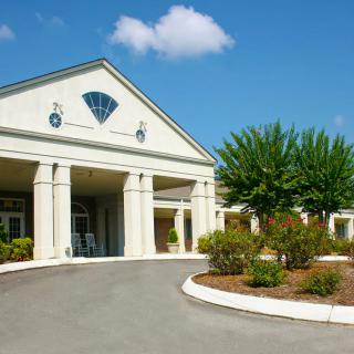 A well-maintained building entrance with columns and landscaped surroundings.