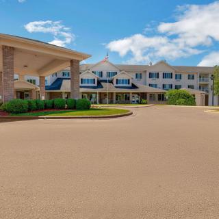 The exterior of a hotel with a large entrance and surrounding landscaping under a blue sky.