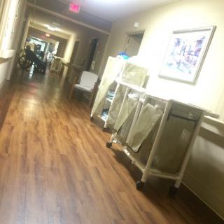 A hospital corridor with medical carts along the side and a brightly lit passage.