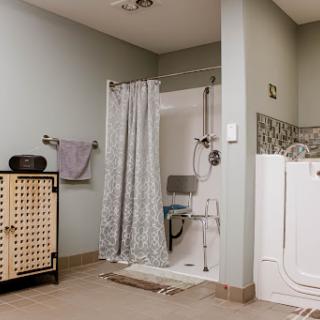 A modern bathroom featuring a shower area with a curtain, towel rack, and storage cabinet.