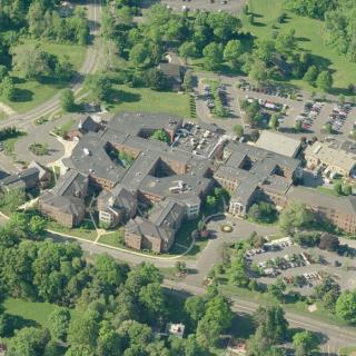 Aerial view of a building complex surrounded by trees and parking areas.