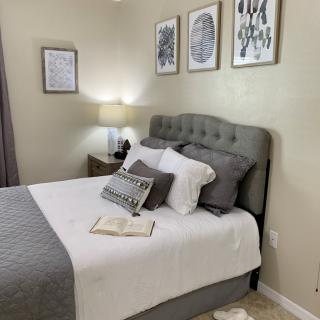 A cozy bedroom with a neatly made bed, decorative pillows, and framed artwork on the wall.