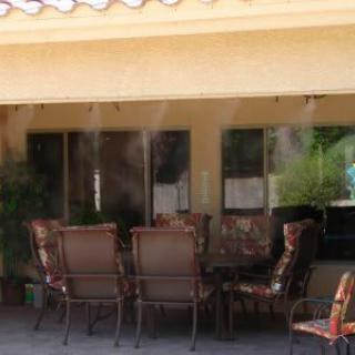 Outdoor patio with a set of chairs and a table under mist cooling system.