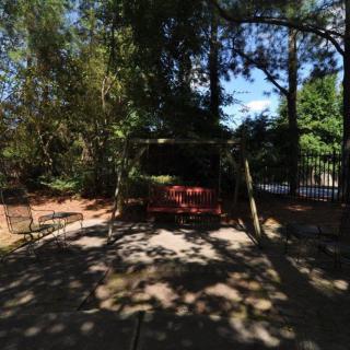 A shaded garden area with a swing surrounded by trees.