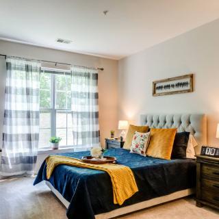 A cozy and well-decorated bedroom with a stylish bed, lamps, and large window curtains.