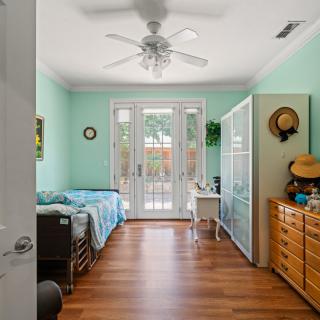 A cozy bedroom with mint green walls, featuring a single bed and glass doors leading outside.