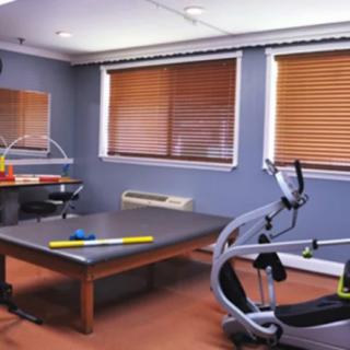 A small fitness room equipped with exercise machines and a therapy table.