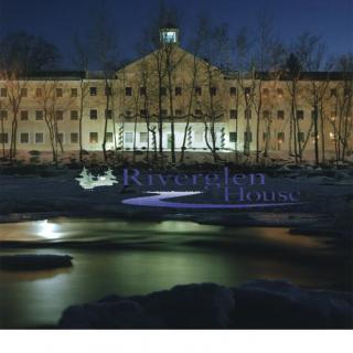 A riverside building illuminated at night with reflections on the water.