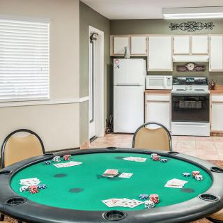 A poker table setup with cards and chips in a room with a kitchen area.