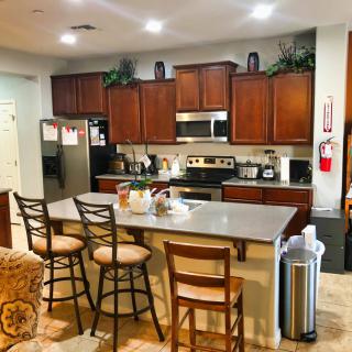 A modern kitchen with wooden cabinets, a spacious countertop, and chairs around a central island.