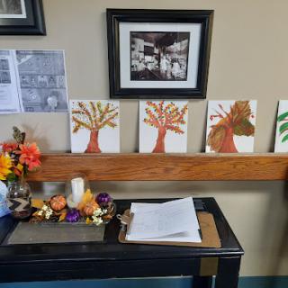 A display of colorful tree paintings along with seasonal decorations, adding a warm touch to the room.
