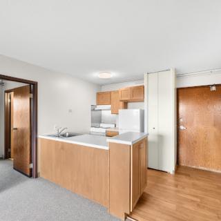 A modern kitchen in an apartment featuring wooden cabinetry and an open layout.