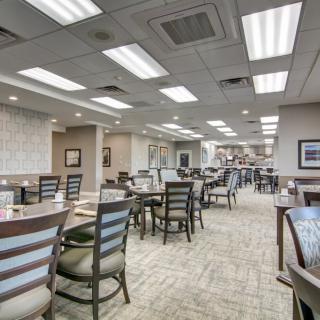 An empty dining area with neatly arranged tables and chairs, well-lit with overhead lighting.