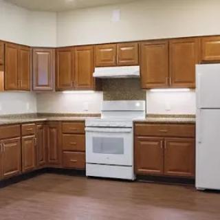 A modern kitchen featuring wooden cabinets and essential appliances.