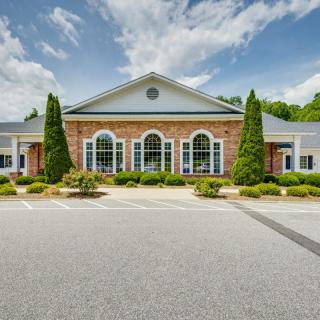 A symmetrical commercial building with brick and white paneling, surrounded by well-maintained landscaping.
