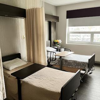 A view of a modern hospital patient room featuring two beds separated by curtains.