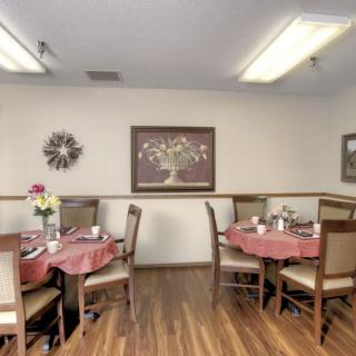 A cozy dining area with neatly arranged tables and chairs, featuring wall art and warm lighting.