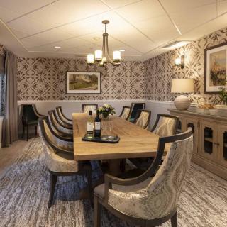 Elegant dining room with a long wooden table, upholstered chairs, and stylish wallpaper.