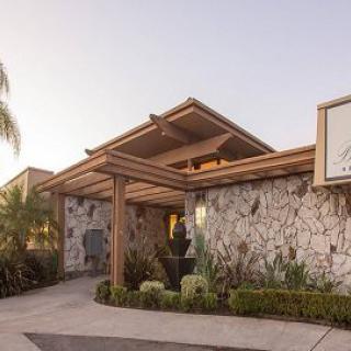 A stone-walled building with a wooden entrance surrounded by landscaping.