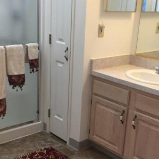 A clean and organized bathroom with a sink, mirror, and shower.