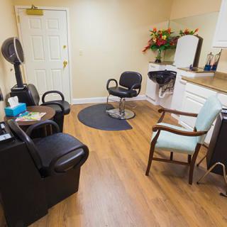A cozy hair salon interior with chairs and a mirror, adorned with flowers.