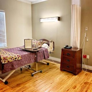 A clean and orderly hospital room with a medical bed, IV stand, and bedside table.