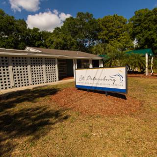 A view of a building with a prominent sign, surrounded by grassy areas and trees.