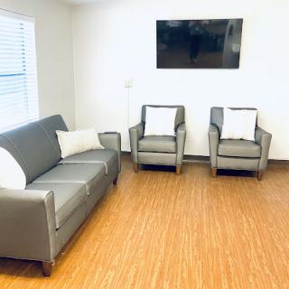 A modern living room setup featuring a gray sofa, two armchairs, and a TV mounted on the wall.