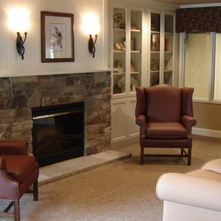 A cozy living room featuring a fireplace, armchairs, and a sofa.