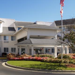 Entrance to a well-maintained building with landscaped surroundings and an American flag.