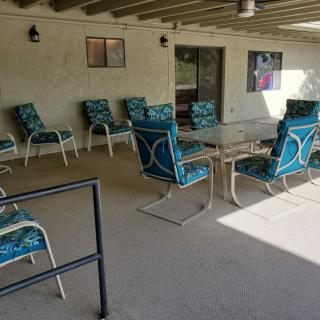 A covered patio with a set of chairs and a table arranged for outdoor seating.