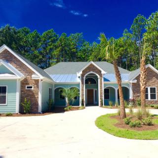 A beautiful house with a spacious driveway surrounded by trees under a clear blue sky.