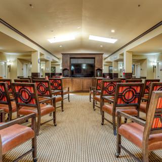 An empty meeting room with rows of chairs facing a central stage.