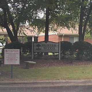 A community sign surrounded by greenery, indicating the presence of a building.