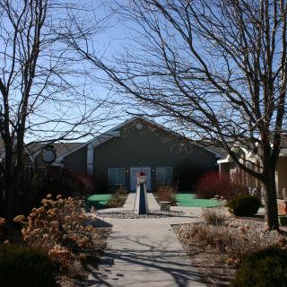 A building surrounded by bare trees and a landscaped path on a sunny winter day.