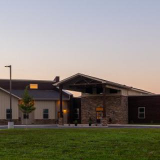 A modern building exterior at sunset with a grassy foreground.