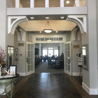 A spacious entrance with double doors and a chandelier leads into a well-lit room.