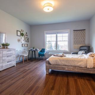 A cozy bedroom with modern decor, featuring a bed, desk, and ample natural light.