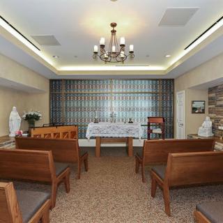 A small chapel interior featuring an altar, wooden pews, and decorative lighting.