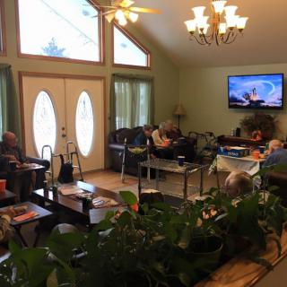 A cozy living room with seniors gathered around, watching television.