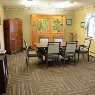 A well-furnished meeting room featuring a table, chairs, and decorative cabinet.