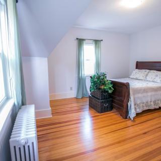A bright, minimalist bedroom with hardwood floors and natural light.