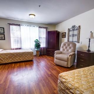 A cozy bedroom with two beds, an armchair, and a wardrobe.