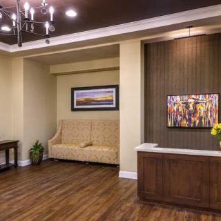 A modern reception area featuring a comfortable sofa, wooden flooring, and decorative artwork on the walls.