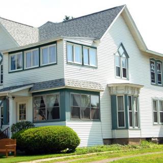 A two-story white house with large windows and a well-maintained yard.