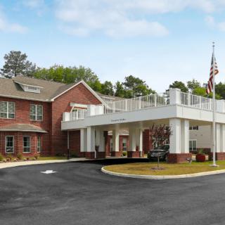 A modern brick building with a covered entrance and an American flag nearby.