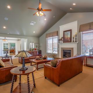 A spacious and elegantly designed living room featuring wooden furniture, a cozy fireplace, and natural lighting from large windows.