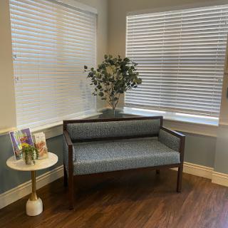 A cozy corner featuring a stylish bench, a decorative plant, and softly lit windows.