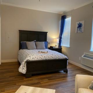 A cozy bedroom with a bed, pillows, and a bedside lamp, featuring wooden flooring and decorative elements.
